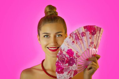 Parlak makyaj ve eller yakın çekim pembe arka plan üzerinde renkli fan ile güzel bir genç kız portresi. Geyşa cosplay