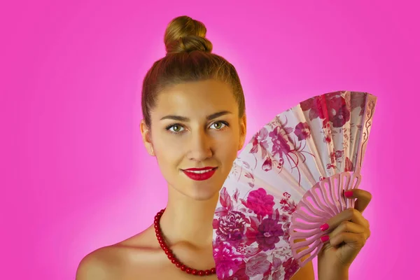 Retrato de una joven hermosa chica con maquillaje brillante y abanico de colores en las manos de cerca en el fondo rosa. Geisha cosplay —  Fotos de Stock