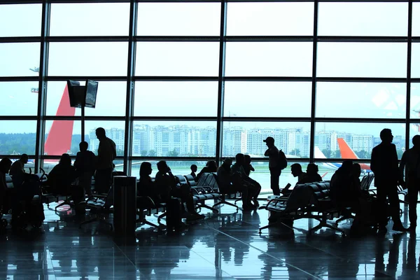 Silhouetten von Menschen, die im Wartezimmer des Flughafens sitzen — Stockfoto