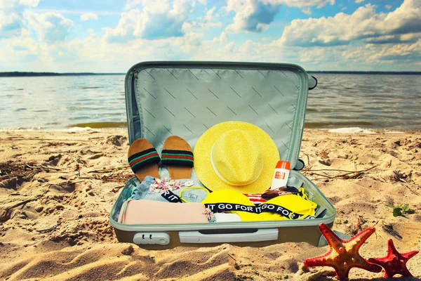 Koper dengan pakaian dan hal-hal yang berbeda untuk perjalanan berbaring menutup di pantai pasir di musim panas — Stok Foto