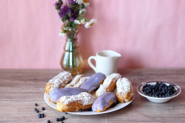 Berry bir vazo kır çiçekleri ve bir sürahi için süt ve yaban mersini ile plaka oluşan bir dekor eklerleri ahşap arka plan üzerinde yaban mersini ile sırlı