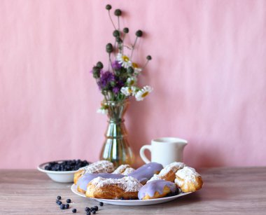 Berry bir vazo kır çiçekleri ve bir sürahi için süt ve yaban mersini ile plaka oluşan bir dekor eklerleri ahşap arka plan üzerinde yaban mersini ile sırlı