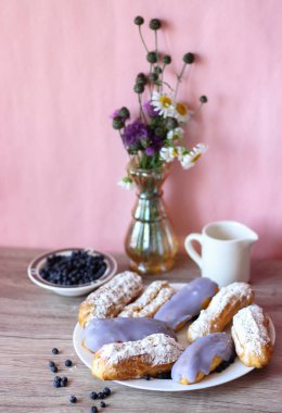 Berry bir vazo kır çiçekleri ve bir sürahi için süt ve yaban mersini ile plaka oluşan bir dekor eklerleri ahşap arka plan üzerinde yaban mersini ile sırlı