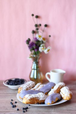 Berry bir vazo kır çiçekleri ve bir sürahi için süt ve yaban mersini ile plaka oluşan bir dekor eklerleri ahşap arka plan üzerinde yaban mersini ile sırlı