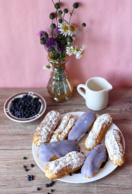 Berry bir vazo kır çiçekleri ve bir sürahi için süt ve yaban mersini ile plaka oluşan bir dekor eklerleri ahşap arka plan üzerinde yaban mersini ile sırlı