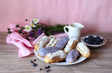 Berry bir vazo kır çiçekleri ve bir sürahi için süt ve yaban mersini ile plaka oluşan bir dekor eklerleri ahşap arka plan üzerinde yaban mersini ile sırlı