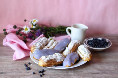 Berry bir vazo kır çiçekleri ve bir sürahi için süt ve yaban mersini ile plaka oluşan bir dekor eklerleri ahşap arka plan üzerinde yaban mersini ile sırlı