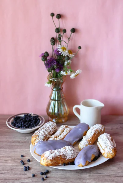 Berry bir vazo kır çiçekleri ve bir sürahi için süt ve yaban mersini ile plaka oluşan bir dekor eklerleri ahşap arka plan üzerinde yaban mersini ile sırlı