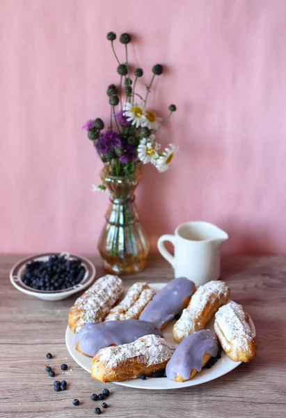 Berry bir vazo kır çiçekleri ve bir sürahi için süt ve yaban mersini ile plaka oluşan bir dekor eklerleri ahşap arka plan üzerinde yaban mersini ile sırlı