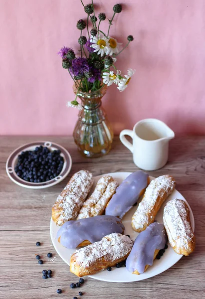Berry bir vazo kır çiçekleri ve bir sürahi için süt ve yaban mersini ile plaka oluşan bir dekor eklerleri ahşap arka plan üzerinde yaban mersini ile sırlı