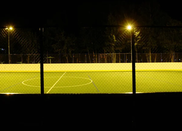 Green football field lit by lanterns in the evening in the summer