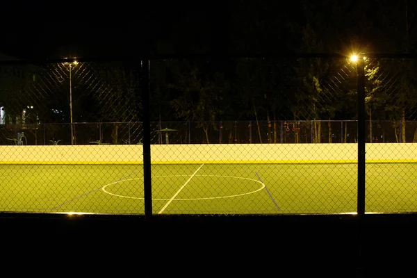 Green football field lit by lanterns in the evening in the summer