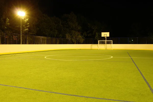 Green football field lit by lanterns in the evening in the summer