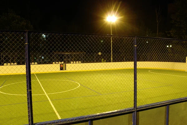 Green football field lit by lanterns in the evening in the summer