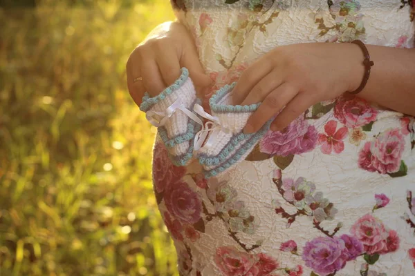 젊은 임신 여자. 공원에서 아기 옷의 클로즈업을 들고 임신한 여자의 손 — 스톡 사진