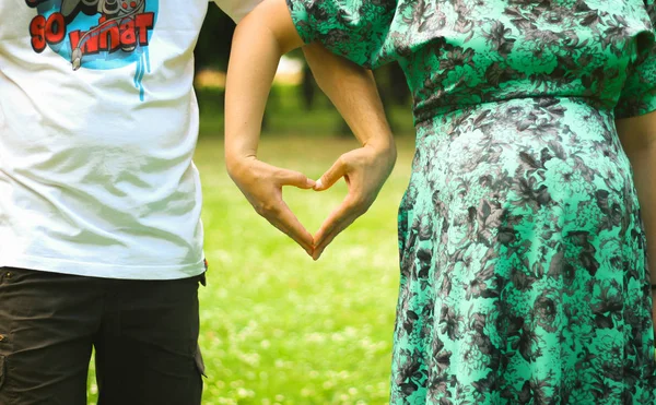 Jovem casal bonito cruzou os braços na forma de um close-up do coração na temporada de verão ao ar livre — Fotografia de Stock