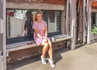 Bankta oturan ve büyük şehirde sabah kahve içme genç güzel sarışın kız