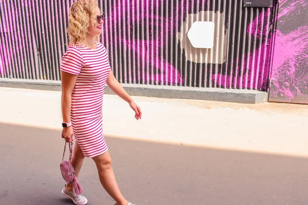 Jovem menina bonita e elegante está andando ao longo da rua no horário de verão — Fotografia de Stock
