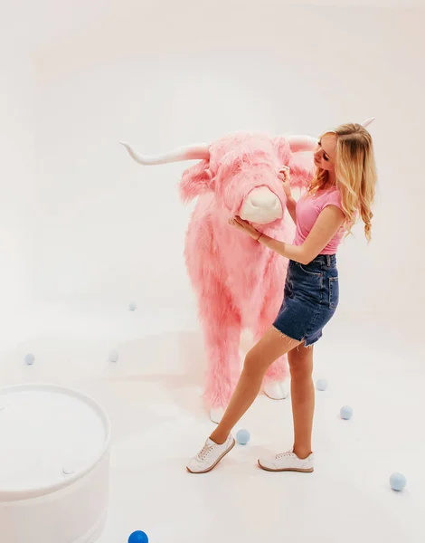 Mladé krásné blondýnka v bílých šatech na bílém pozadí s Fantastické scenérie s pink bull — Stock fotografie