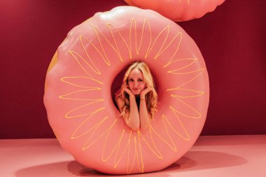 Genç güzel sarışın kız pembe çörek arka plan üzerinde.