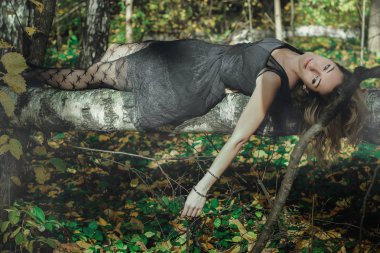 Çeşitli pozlar mistik bir ormanda siyah bir maske ile genç tür cadı siyah elbise giymiş. İşleme sanatı.