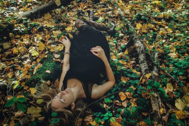 Çeşitli pozlar mistik bir ormanda siyah bir maske ile genç tür cadı siyah elbise giymiş. İşleme sanatı.