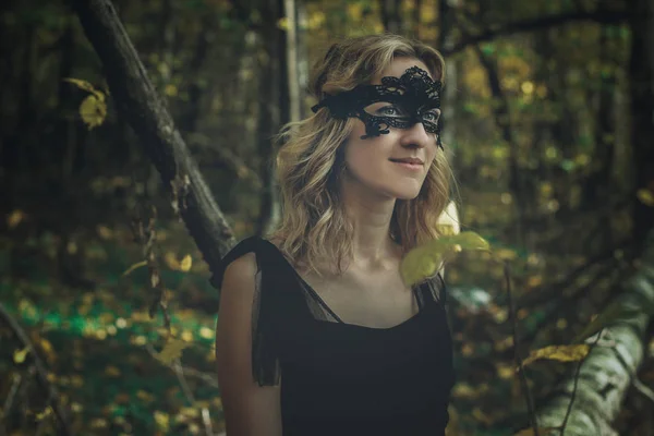 一个年轻的女巫在黑色的礼服与黑色面具在一个神秘的森林中的各种姿势 艺术加工 — 图库照片