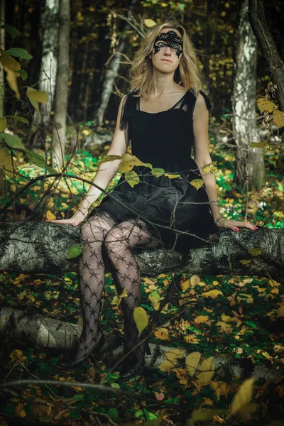 一个年轻的女巫在黑色的礼服与黑色面具在一个神秘的森林中的各种姿势 艺术加工 — 图库照片