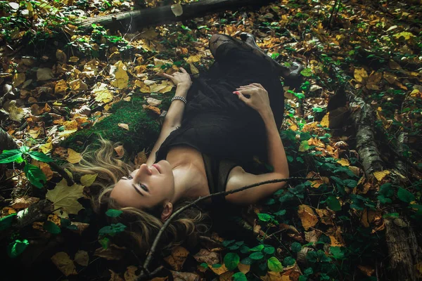 若い親切な魔女黒のドレスで様々 なポーズで神秘的な森で黒マスクを使用 アート処理 — ストック写真