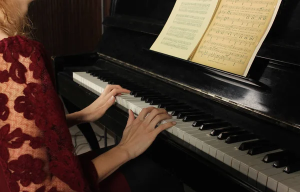 Молодая красивая женщина играет на черном фортепиано крупным планом — стоковое фото