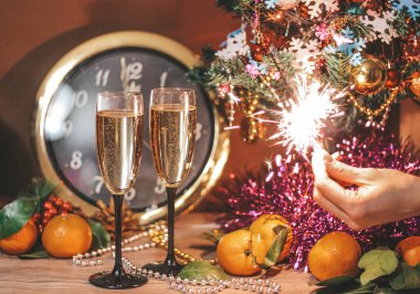Saat, oluşan Noel kompozisyon hangi saat 12 yönünde, bardak şampanya kabarcıklar ile bir kızın elinde havai fişekleri oktur.