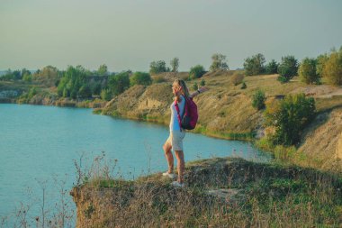 Pembe sırt çantası olan kadın arka plan günbatımı zamanında kapatmak mavi tebeşir ocaklar üzerinde duruyor