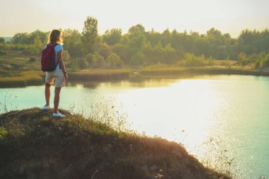 Pembe sırt çantası olan kadın arka plan günbatımı zamanında kapatmak mavi tebeşir ocaklar üzerinde duruyor