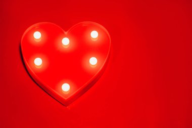 Kırmızı kalp kırmızı arka plan portre üzerinde el feneri ile parlayan.