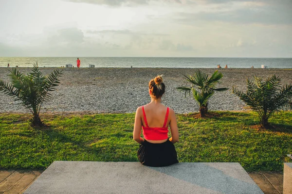 Joven chica atractiva en una camisa roja sentada cerca del mar en el verano, Batumi, Georgia —  Fotos de Stock