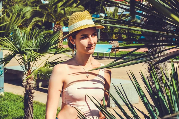 Young attractive girl in a swimsuit close up among palm trees — 스톡 사진