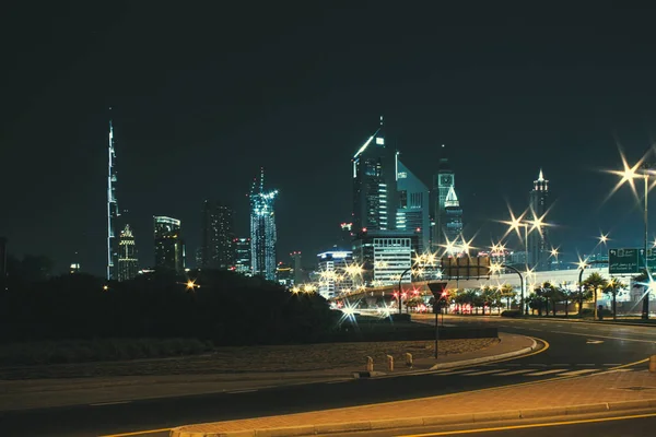 Paisaje nocturno con vistas a los rascacielos y el Burj Khalifa desde el lado de la carretera — Foto de Stock