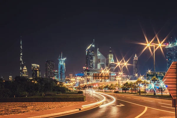 Paisaje nocturno con vistas a los rascacielos y el Burj Khalifa desde el lado de la carretera — Foto de Stock