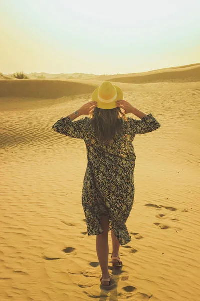 Joven chica hermosa en un vestido largo y un sombrero en el medio del desierto durante el día —  Fotos de Stock