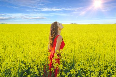 Kırmızı bir elbise genç güzel kız turp çiçekler ve sunligh ile sarı alanın ortasında yakın
