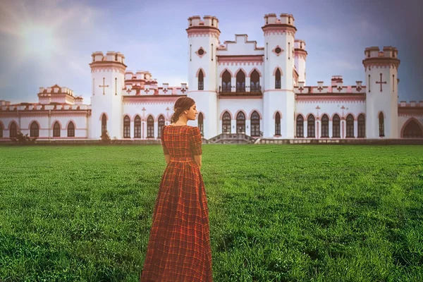 Young beautiful princess in a long red dress on the castle background in sunny day. Art processin — Stock Photo, Image