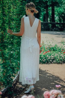 Çiçekleri ile yeşil bahçede beyaz elbiseli genç güzel kadın yaz aylarında yakın