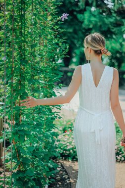 Çiçekleri ile yeşil bahçede beyaz elbiseli genç güzel kadın yaz aylarında yakın