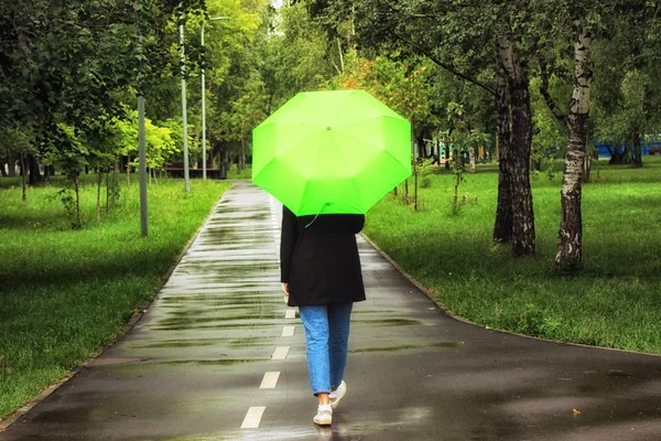 Ung vacker flicka som går ensam under grönt paraply i stadsparken på sommaren — Stockfoto