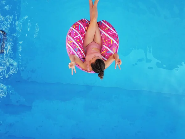 Menina bonita jovem relaxante e nadando na piscina azul com um círculo rosa closeu — Fotografia de Stock