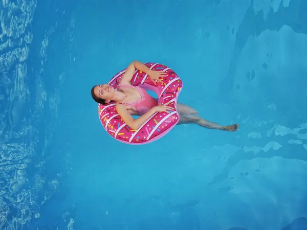 Menina bonita jovem relaxante e nadando na piscina azul com um círculo rosa closeu — Fotografia de Stock