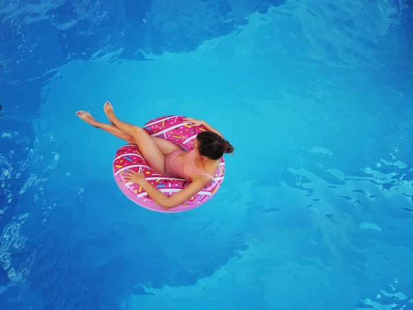 Krásná mladá dívka, odpočinek a koupání v modré bazénu se růžový kruh Deta — Stock fotografie