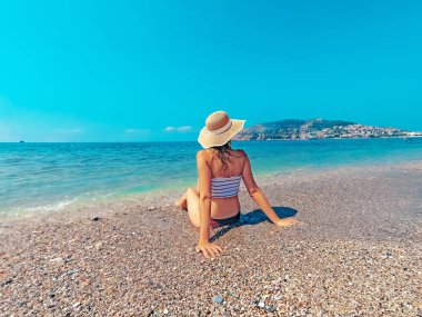 Genç güzel kadın deniz maliyet üzerinde oturuyor ve dalgalar manzara zevk. Alanya, Türkiye