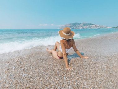 Genç güzel kadın deniz maliyet üzerinde oturuyor ve dalgalar manzara zevk. Alanya, Türkiye