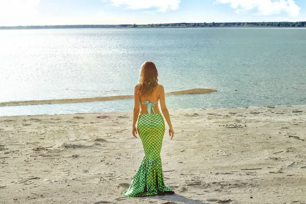 Young beautiful mermaid woman close up standing on the sea cost.
